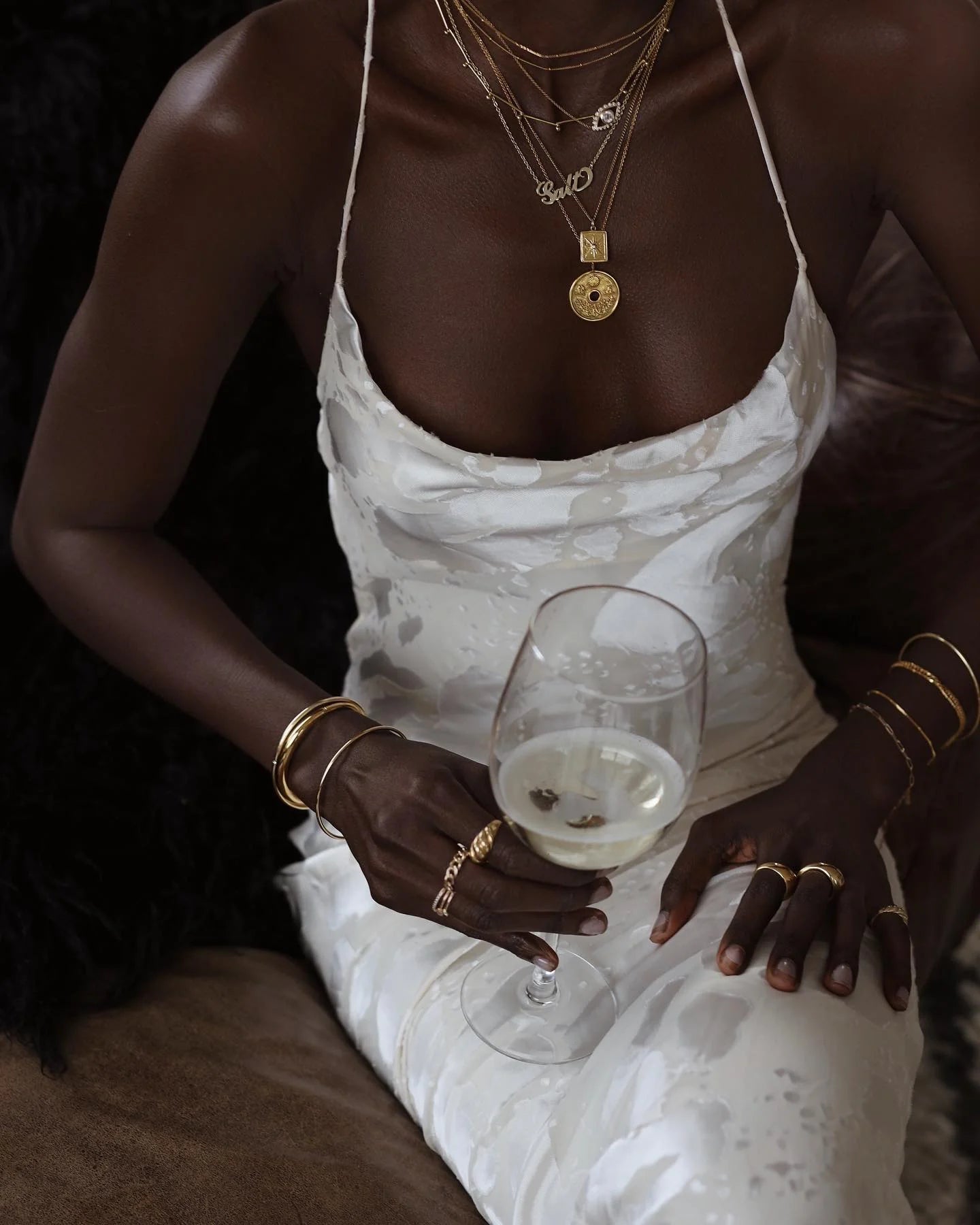 A woman in a white dress holding a glass of wine.
