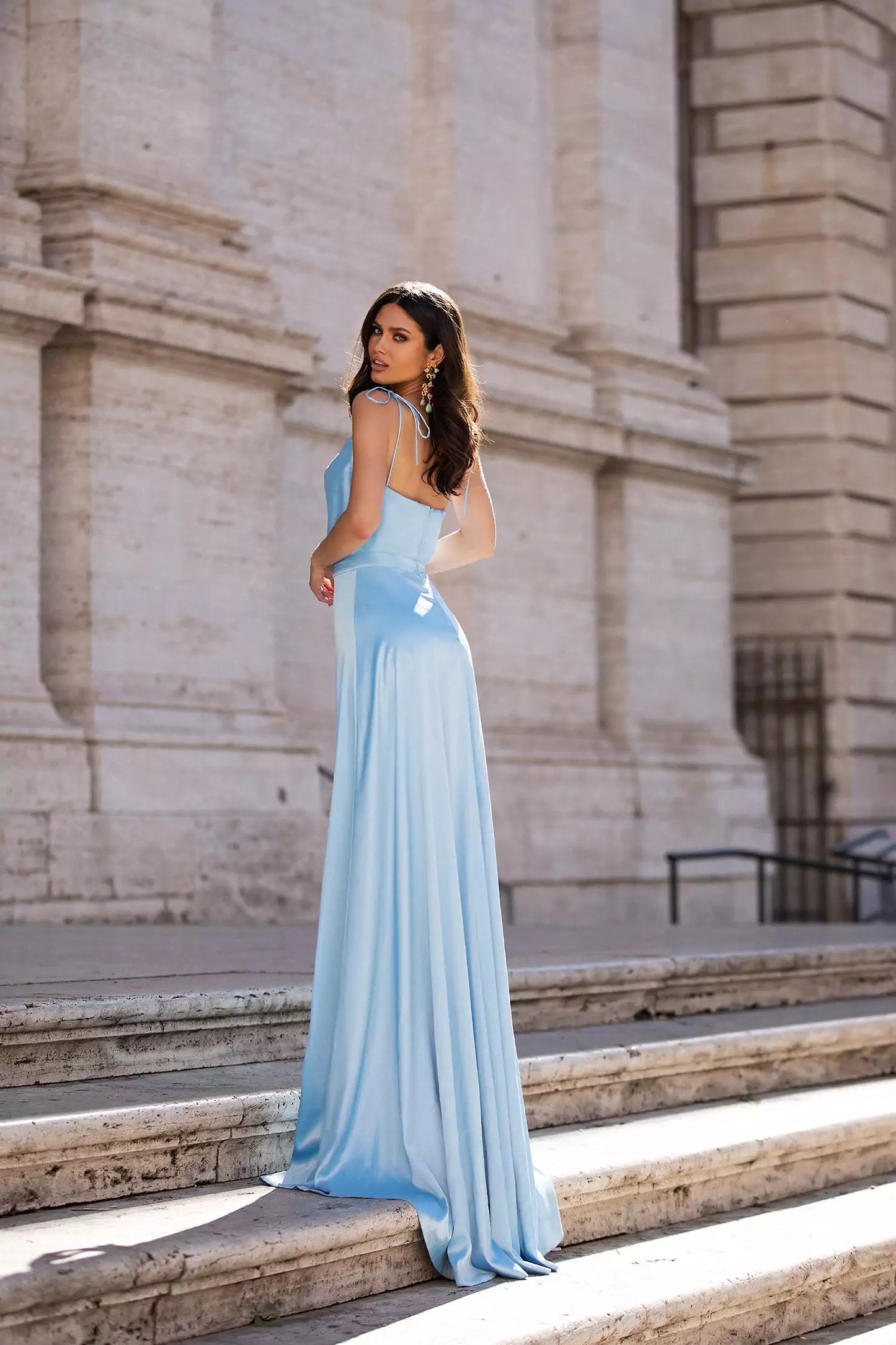 A woman in a blue dress posing in front of a building.