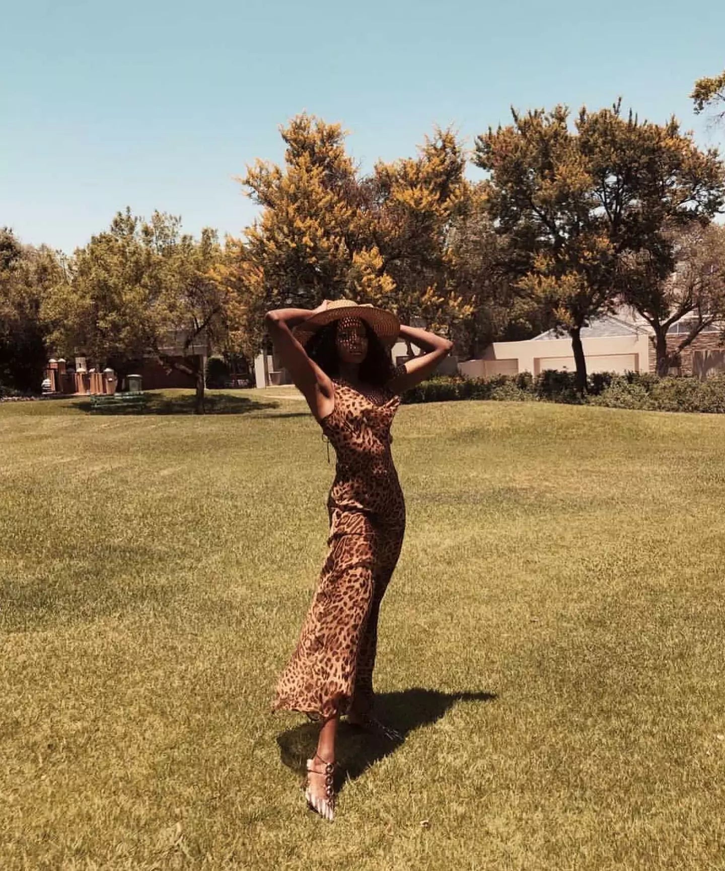 A woman in a leopard print dress standing on a grassy field.