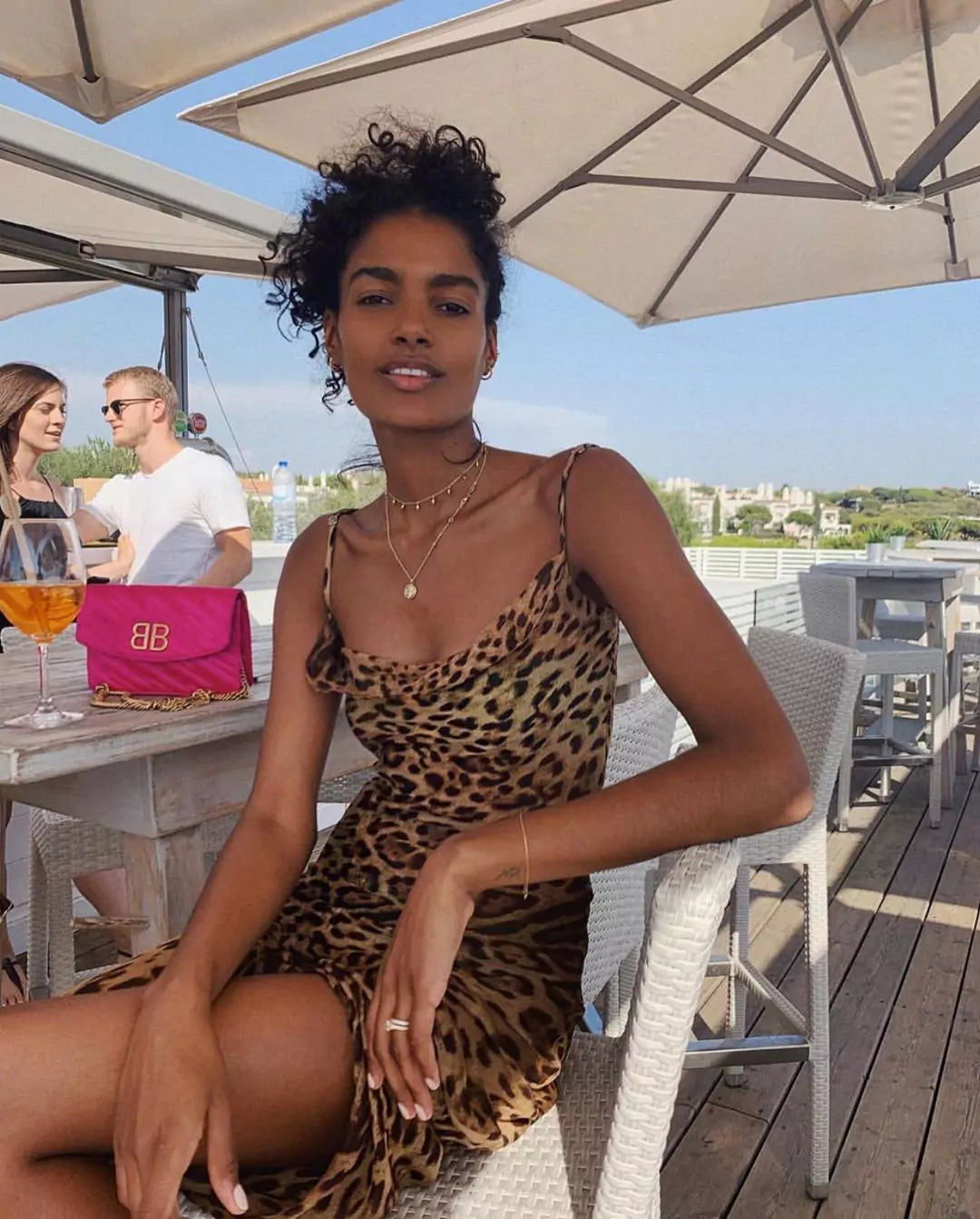 A woman in a leopard print dress sitting on a chair.