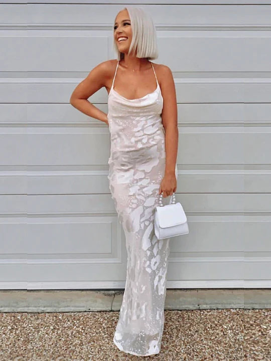A woman in a white dress standing in front of a garage.