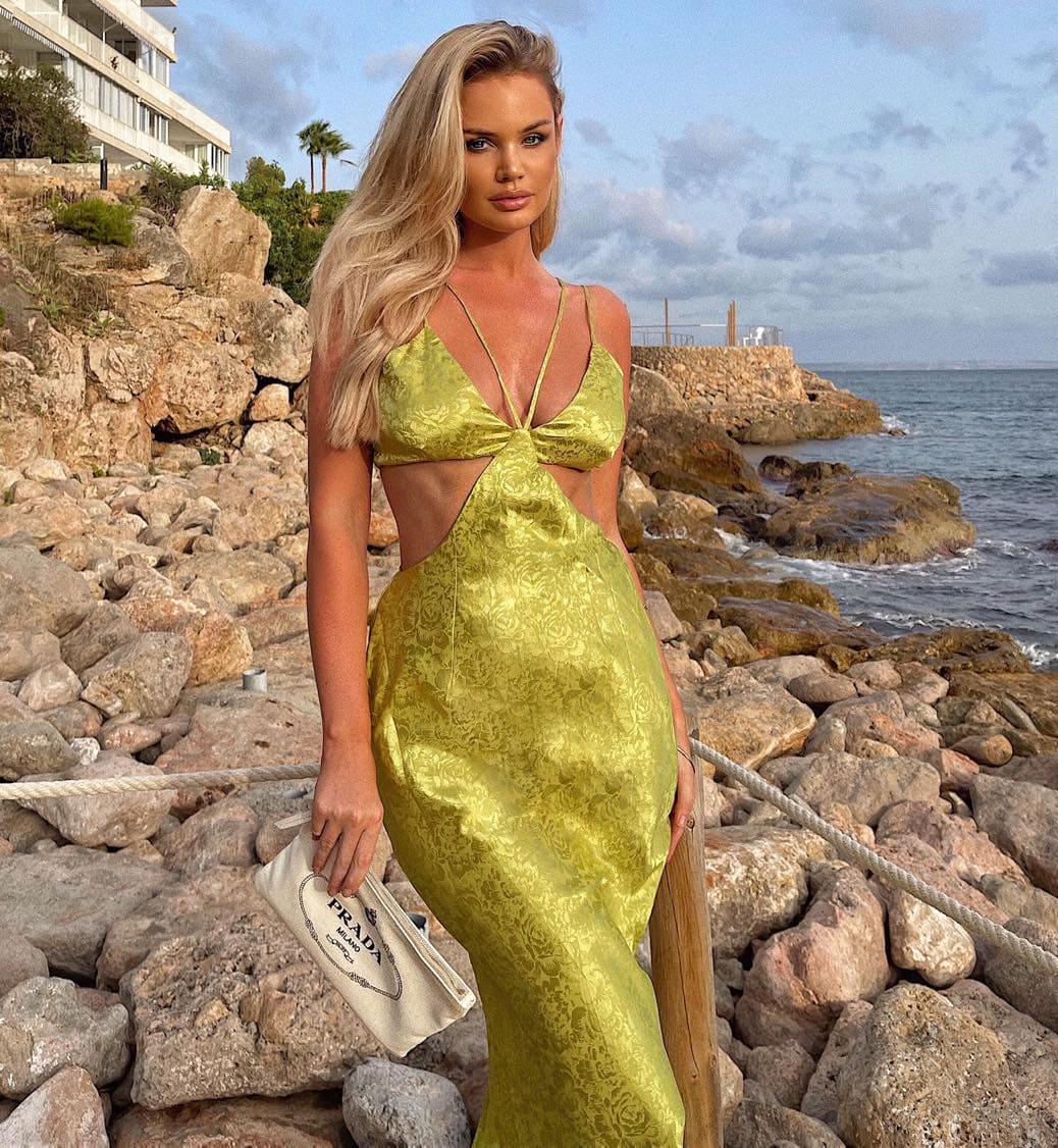 A woman in a yellow dress posing on the rocks.