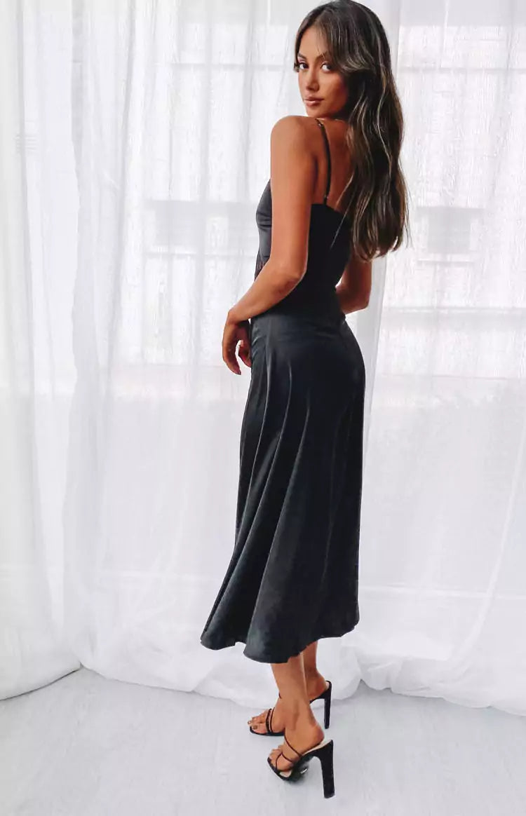 The model is wearing a black satin midi dress.