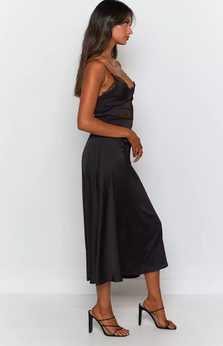 The model is wearing a black satin slip dress.