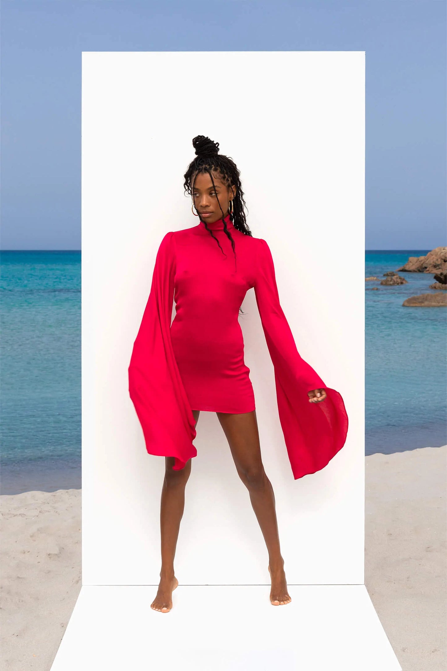 A woman in a pink dress posing on the beach.