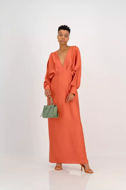 A woman in an orange maxi dress holding a green handbag.