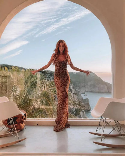 A woman in a leopard print dress standing in front of a window.