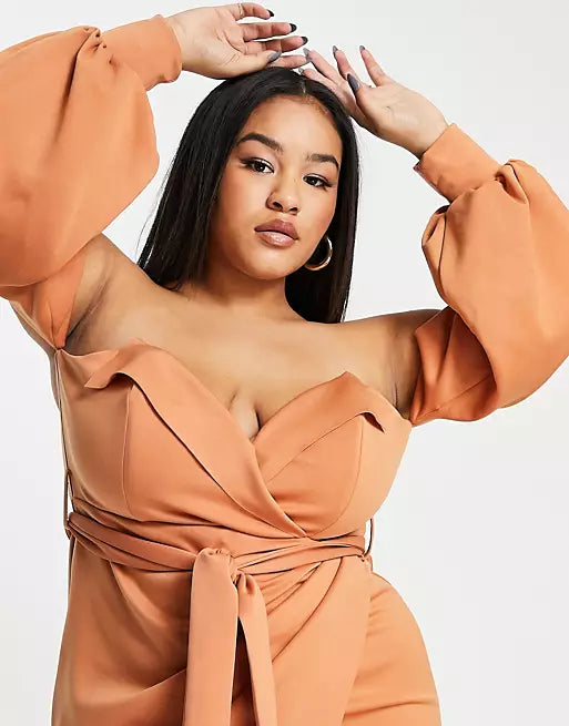 A plus size woman wearing a tan sleeved bodycon dress.