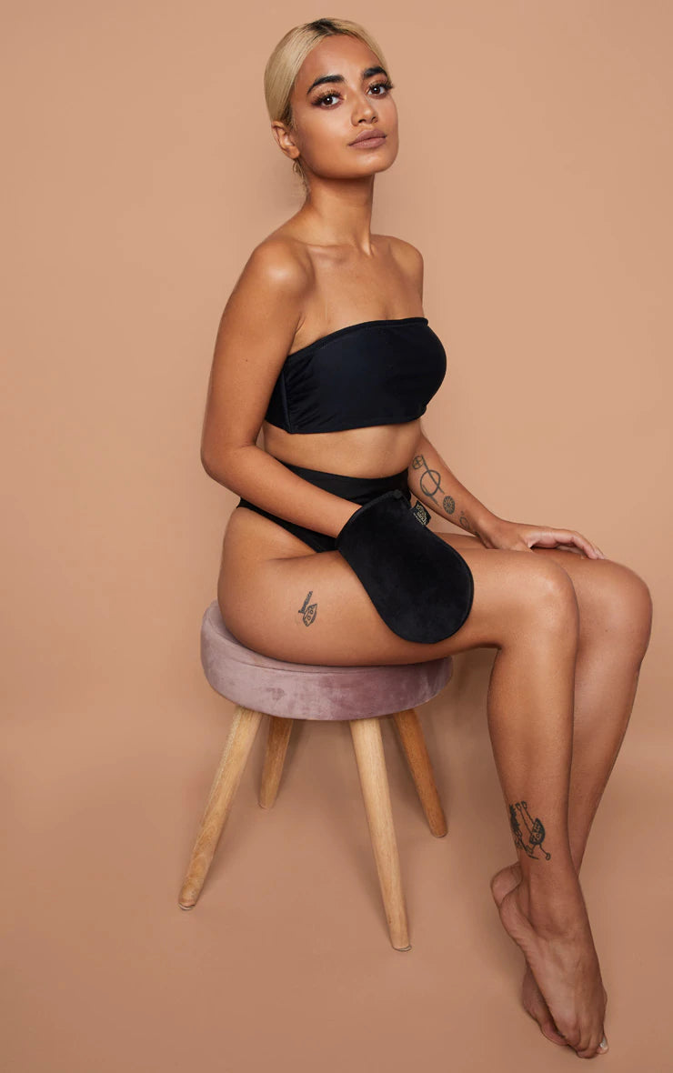 A woman sitting on a stool in a black bikini.