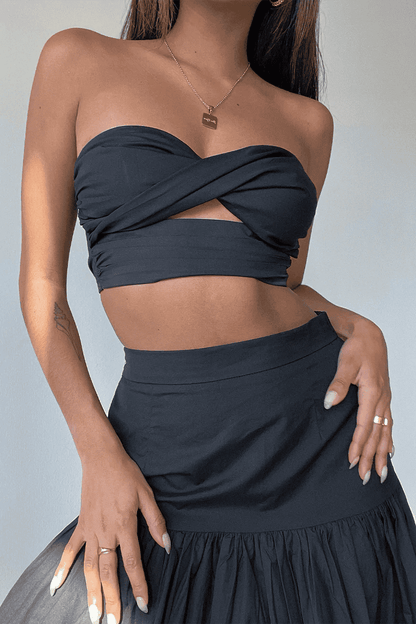 A woman wearing the Vittoria set, consisting of a black crop top and skirt from Runaway The Label.