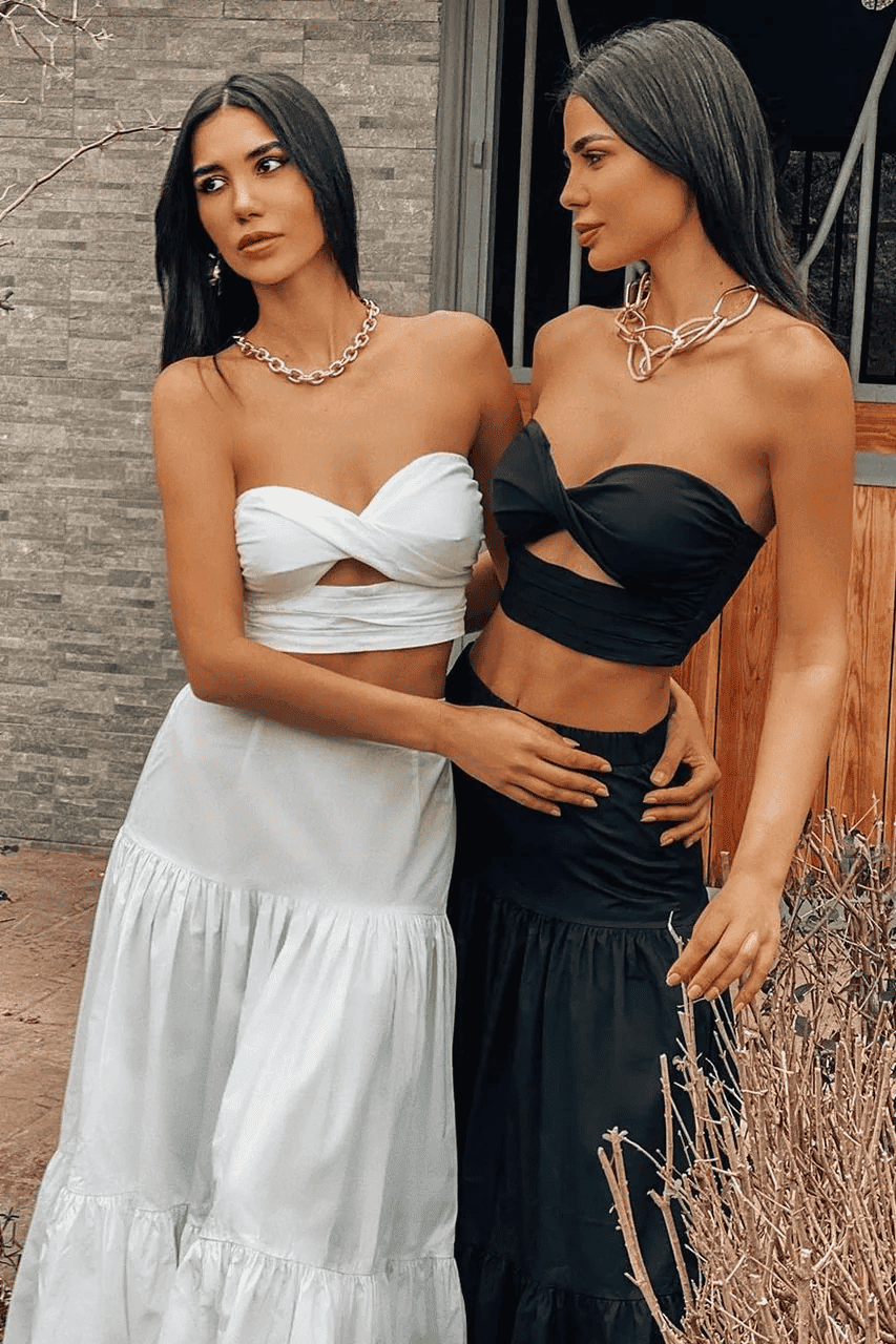 A woman wearing a black crop top and skirt.