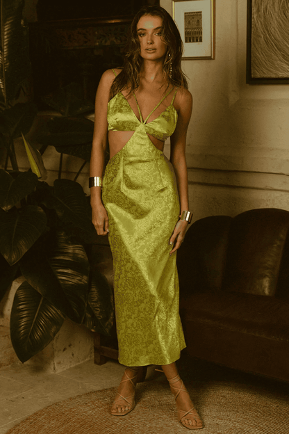 A South African woman in a lime dress from Runaway The Label posing in front of a couch