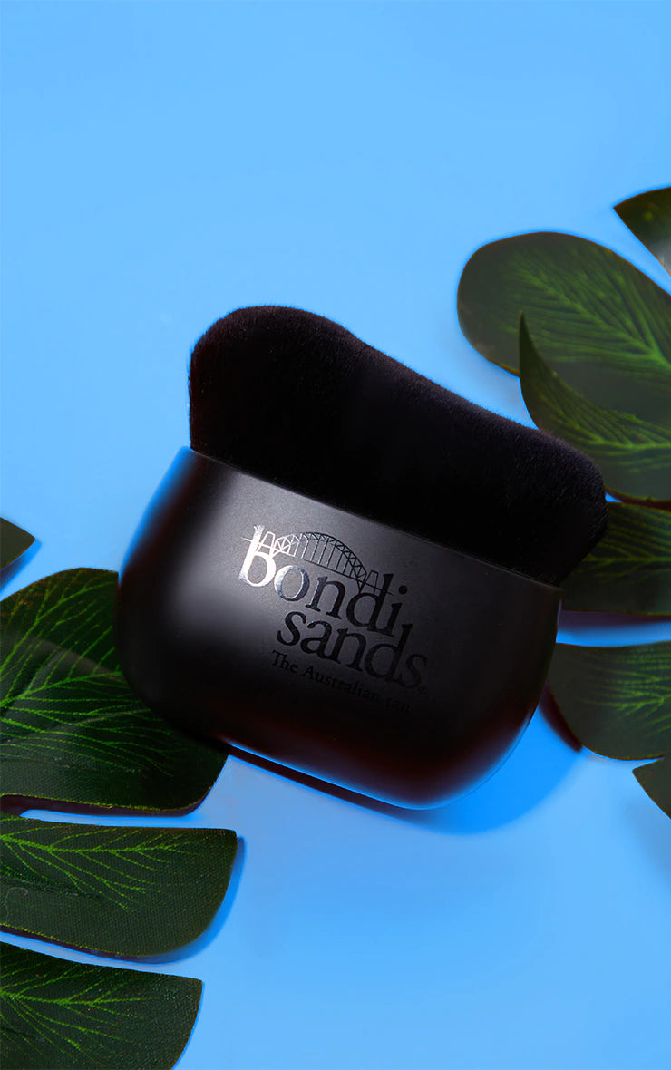 The Bondi Sands body brush on a blue background.